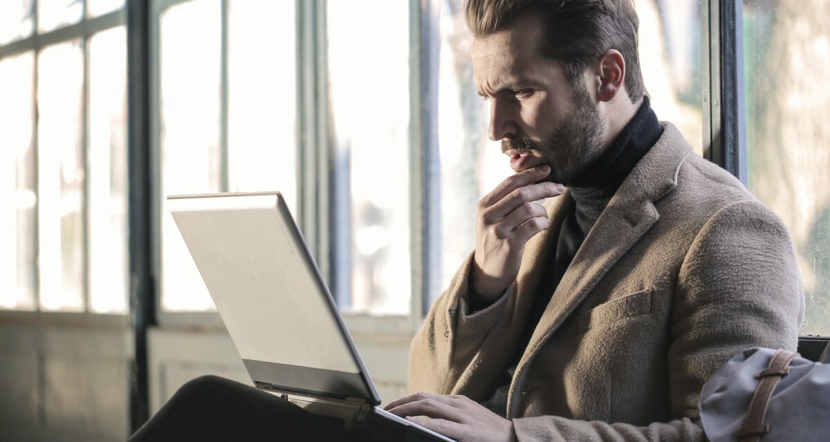 hombre sujetando su barbilla frente al ordenador portátil