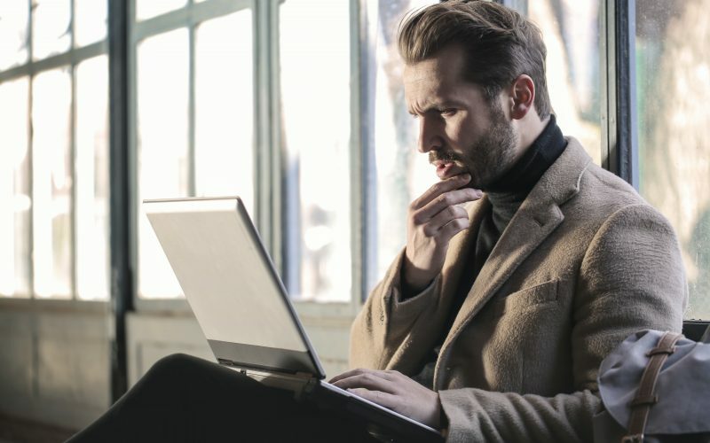 hombre sujetando su barbilla frente al ordenador portátil
